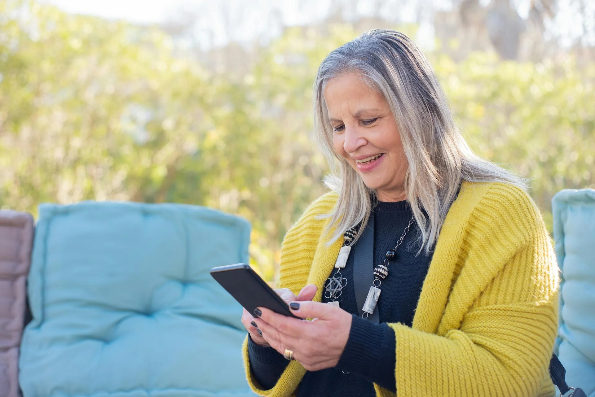 A woman smiling while looking at her phone outdoors